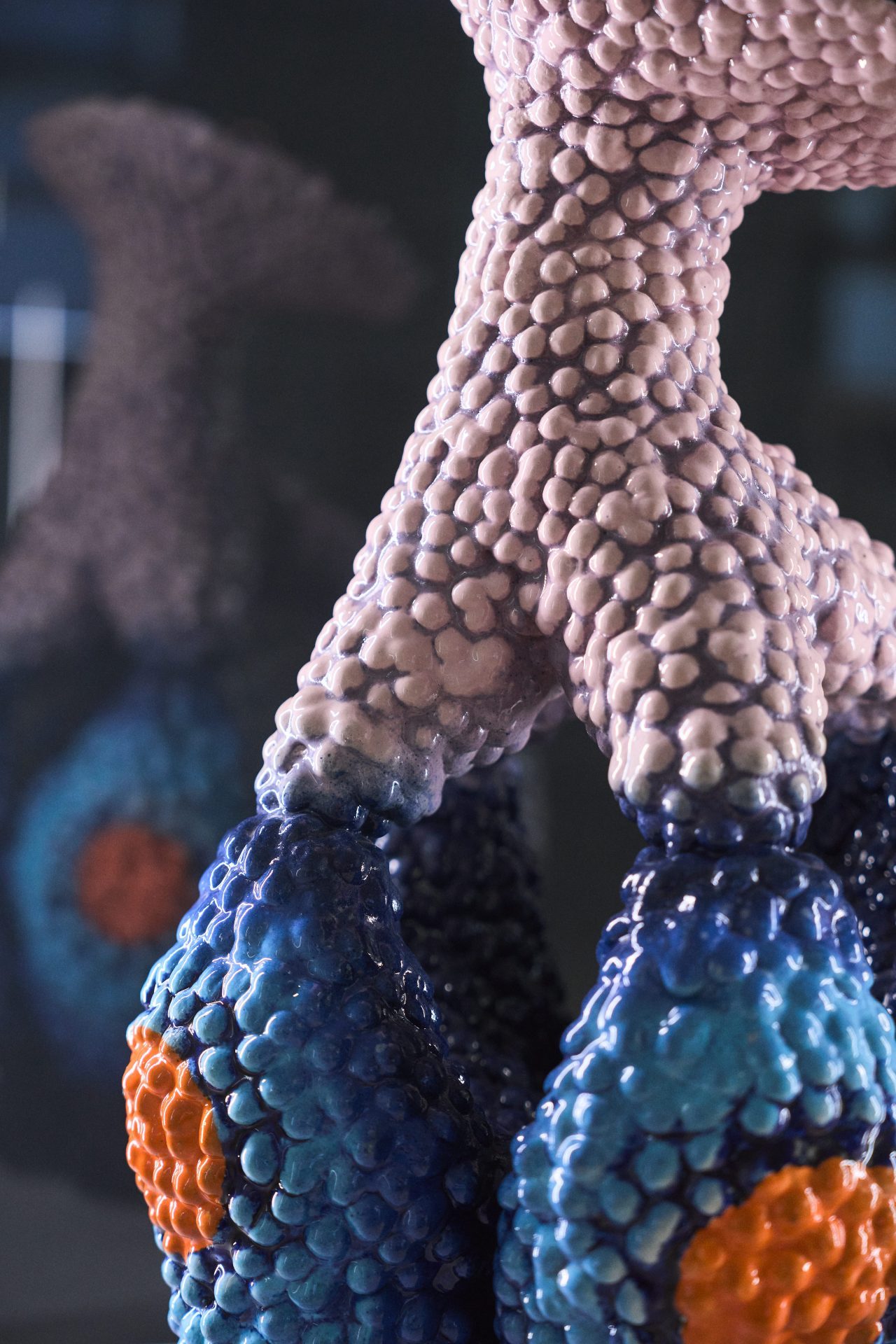 Abstrakte Skulptur mit organischen, strukturierten Oberflächen in sanften Blau-, Orange- und Pinktönen.