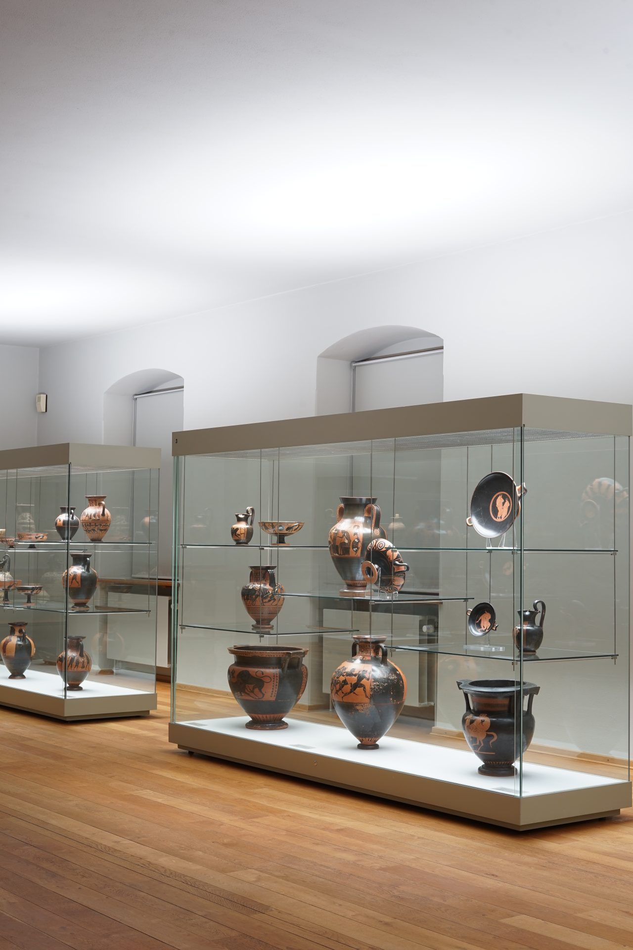 Ausstellung antiker Töpferwaren, beleuchtet in einem modernen Ausstellungsraum.