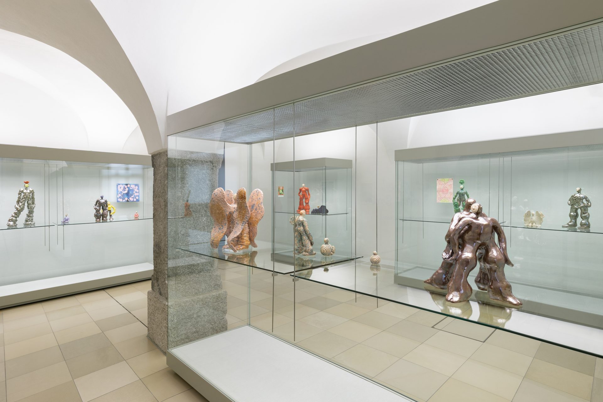 Moderne Kunstgalerie mit Skulpturen in Glaskästen und minimalistischer Architektur.