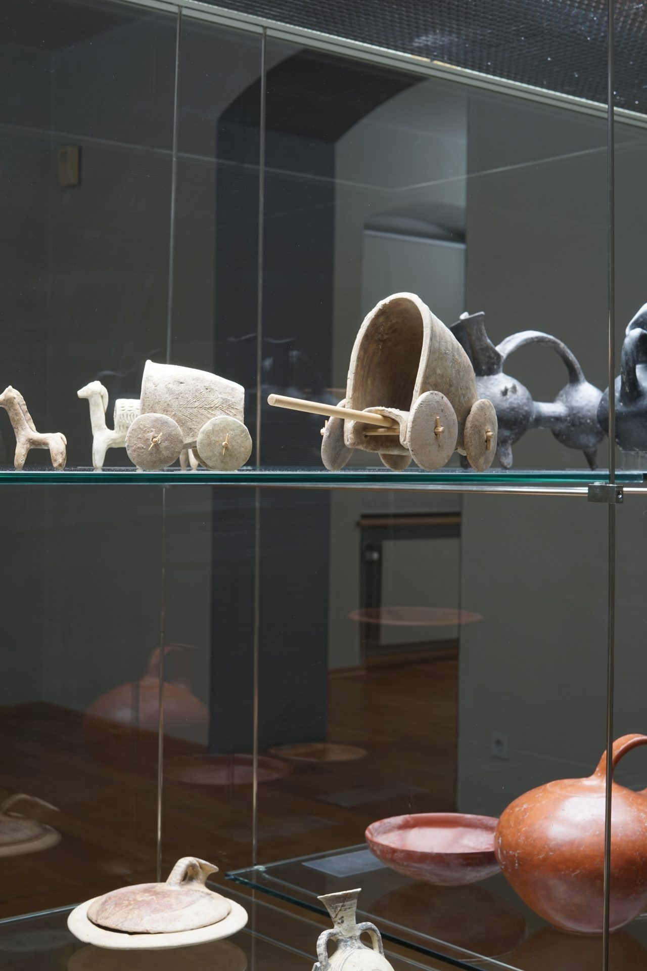 Vitrine mit antiken Keramikeinheiten und Modellfahrzeugen, sichtbar in verschiedenen Formen und Designs.