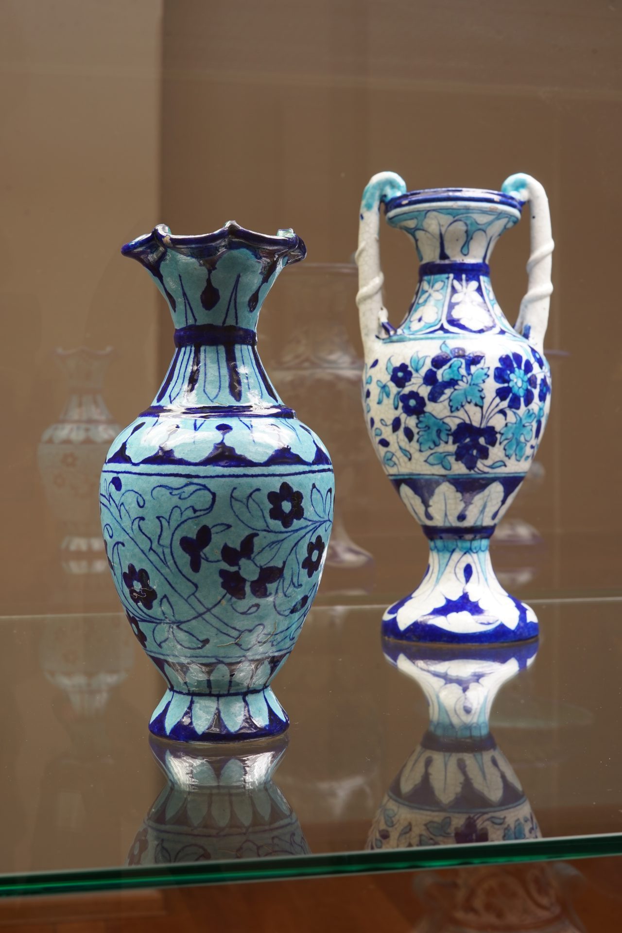 Zwei dekorative Keramikwaren in Blau- und Türkistönen, kunstvoll mit floralen Mustern bemalt.