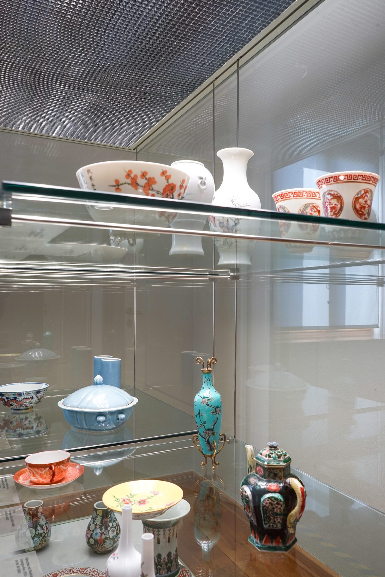 Historische Keramiken in einer Vitrine: Schalen, Tassen und Vasen in verschiedenen Farben und Stilen.