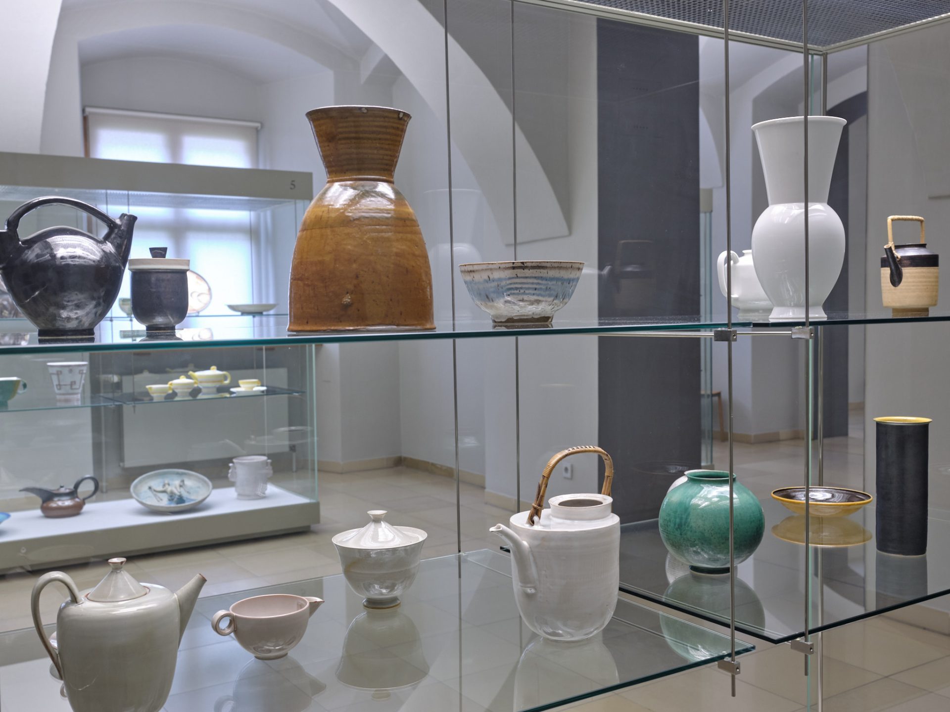 Keramikausstellung in Glasvitrinen mit verschiedenen Formen und Farben.