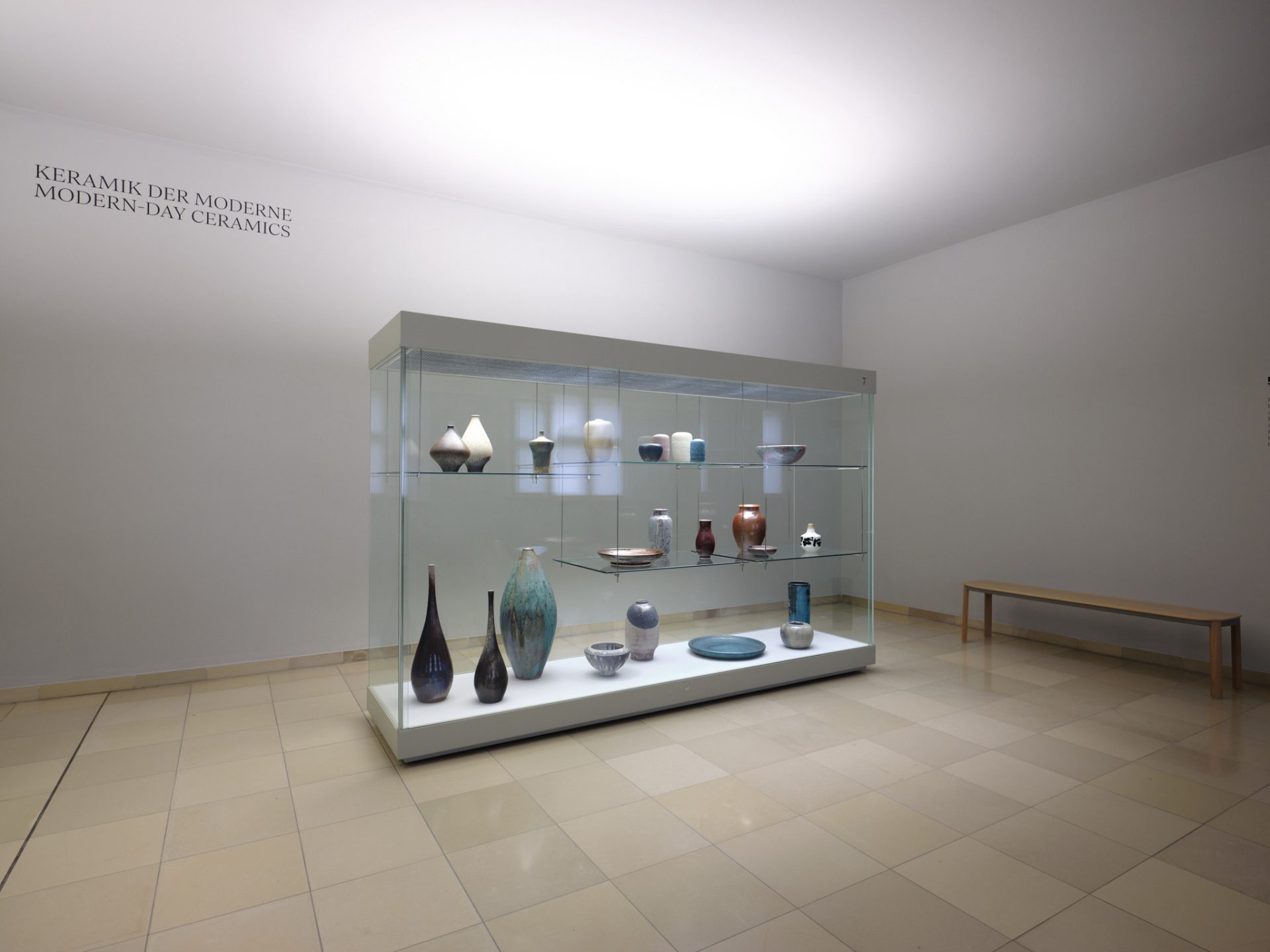 Moderne Keramiken, darunter Vasen und Schalen, präsentieren sich in einem minimalistischen Ausstellungsraum.