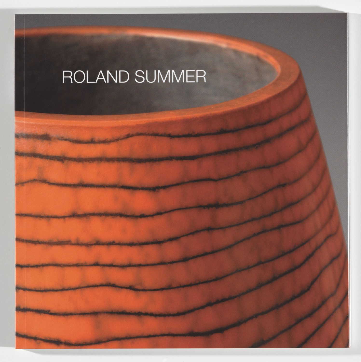 Nahaufnahme eines Buchcovers mit dem Titel "Roland Summer" und einer orangefarbenen, gestreiften Oberfläche.
