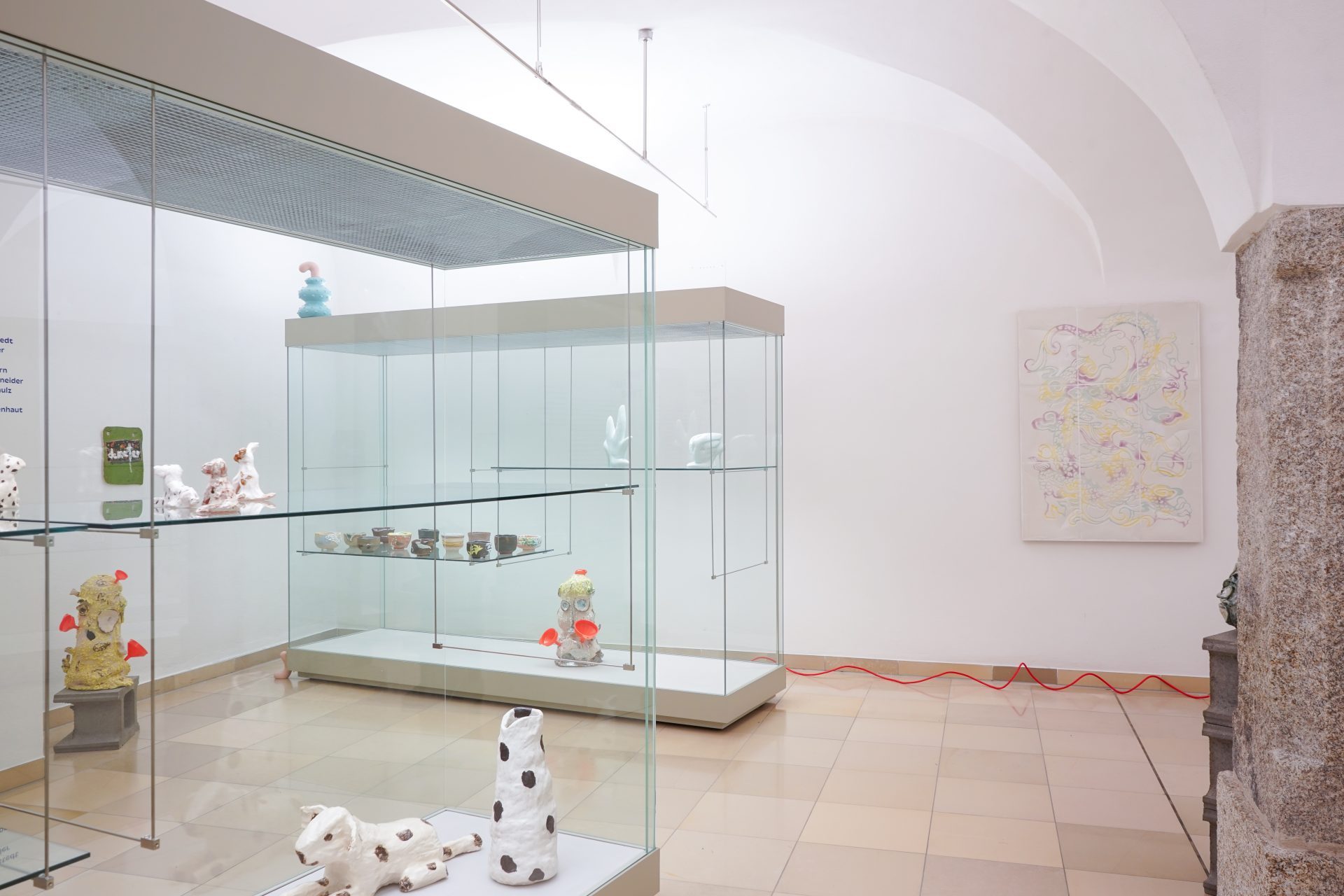 Moderne Galerie mit Glaskästen, die bunte Skulpturen und Kunstwerke zeigen. Minimalistisches Raumdesign.