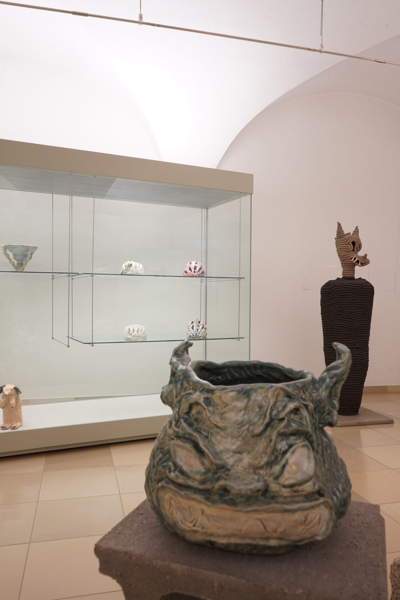 Skulpturen und Keramiken in einem Ausstellungsraum, mit einer auffälligen tierähnlichen Figur im Vordergrund.